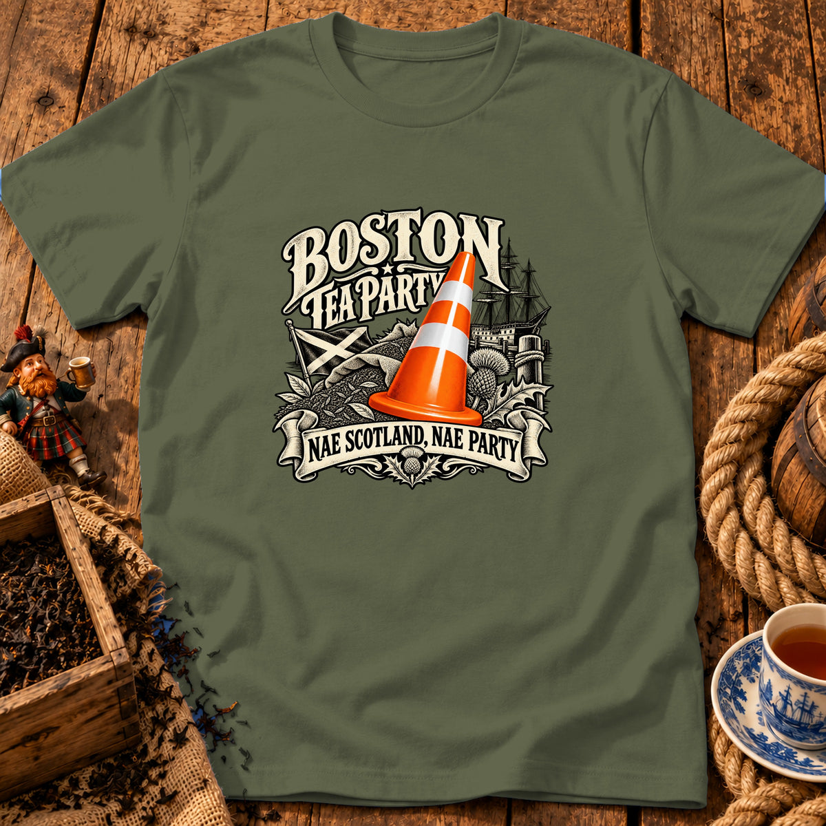 An olive green t-shirt features a graphic with an orange traffic cone, a sailing ship, and the text Boston Tea Party and Nae Scotland, Nae Party.