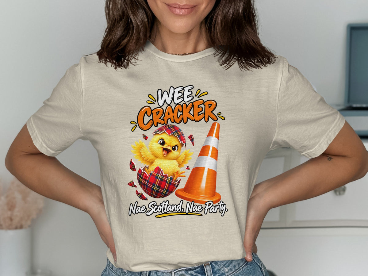 Chick hatching from tartan egg, Wee Cracker text, and traffic cone.