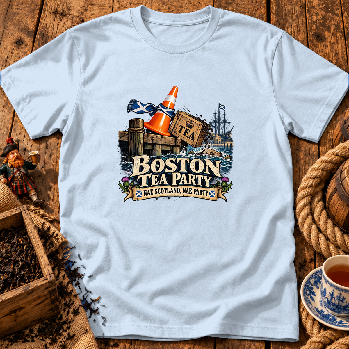 A light blue t-shirt with a graphic of a Scottish-themed Boston Tea Party illustration.