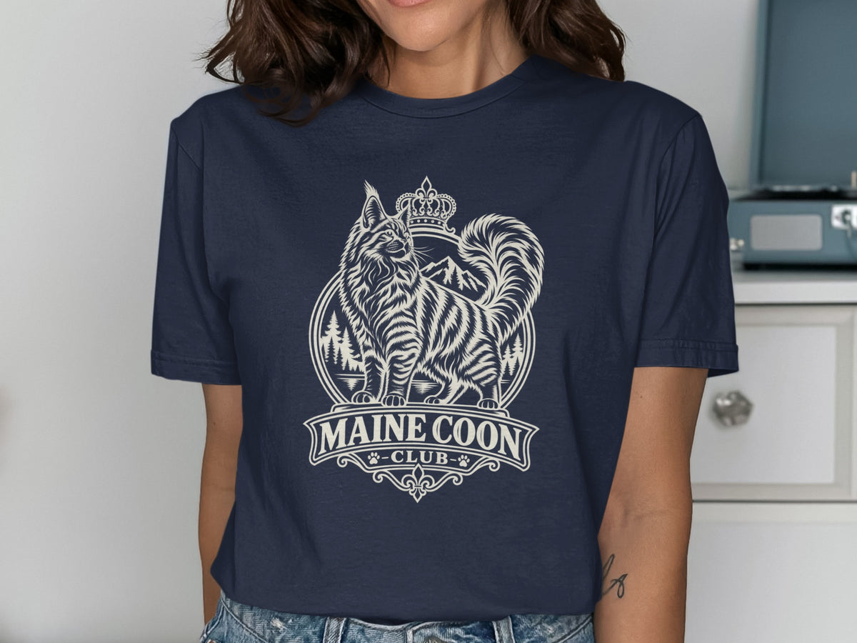 Maine Coon Club graphic on navy t-shirt featuring crowned cat and mountains.