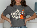 T-shirt graphic with text "LAST ORDERS, SANTA." and a traffic cone with a scarf.