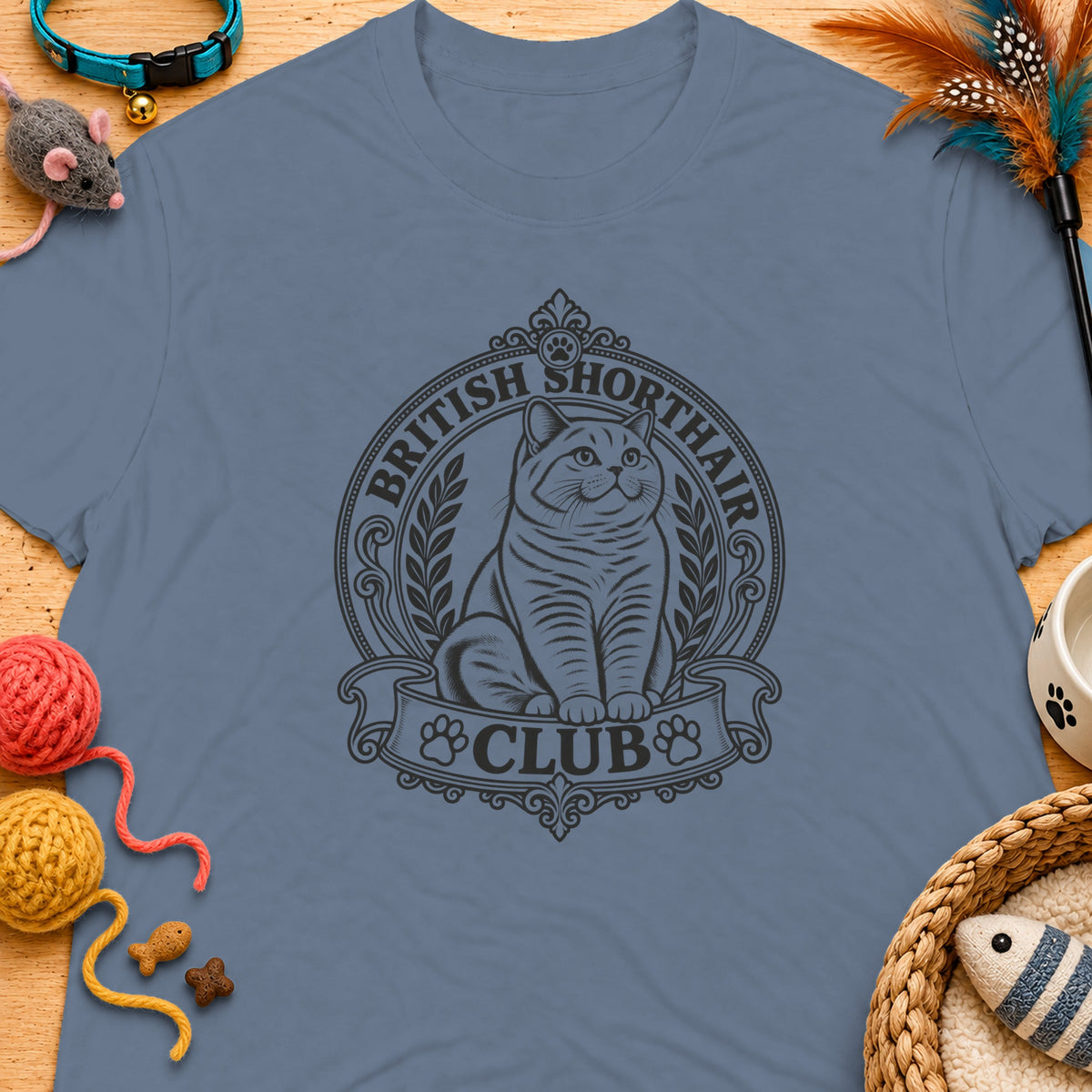 British Shorthair Club emblem on a blue t-shirt with cat toys.