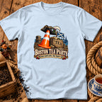 A light blue t-shirt with a graphic of a pirate hat, traffic cone, and tea crate, featuring the text "Boston Tea Party, Nae Scotland, Nae Party".