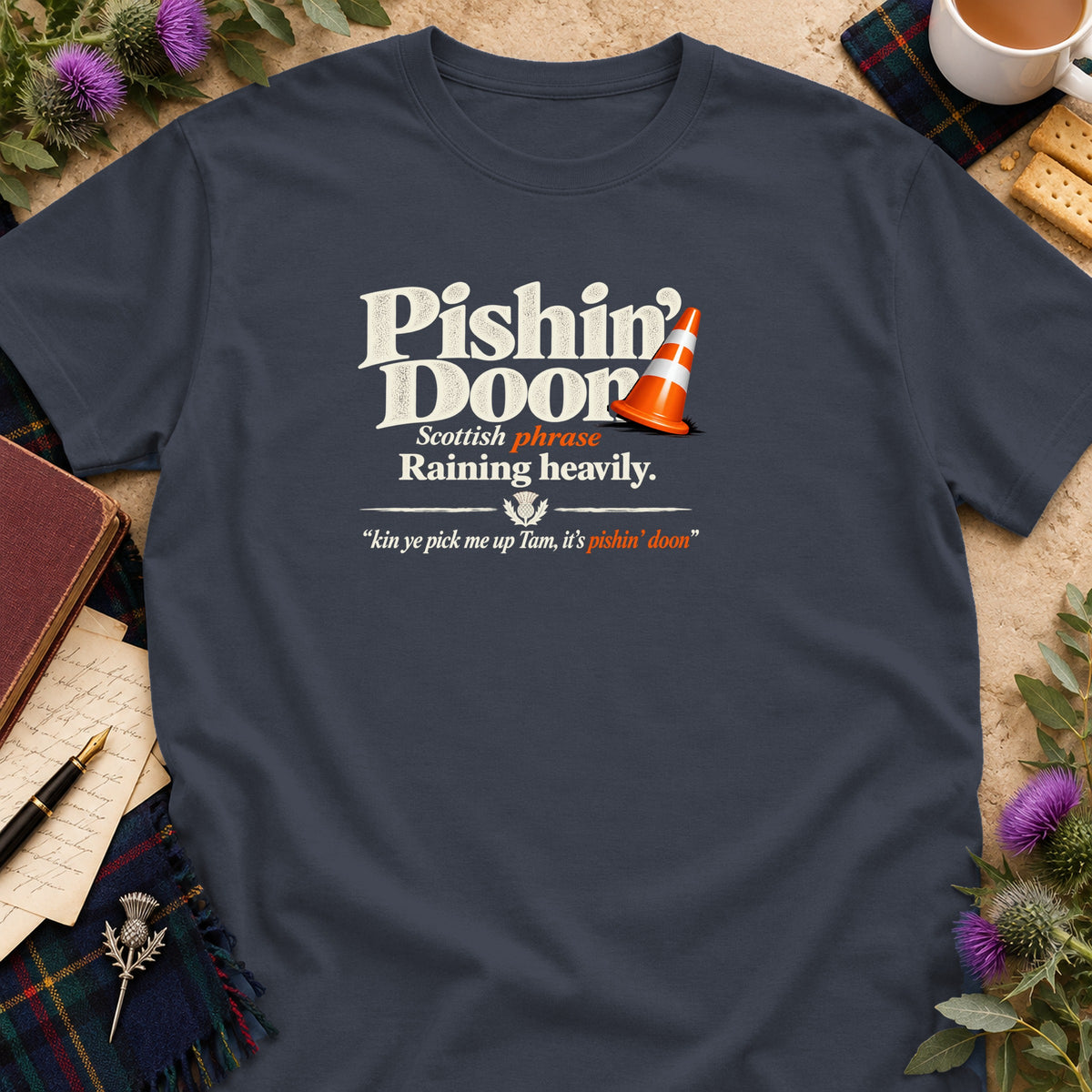 A dark gray t-shirt featuring text and a traffic cone, surrounded by books and thistle flowers.