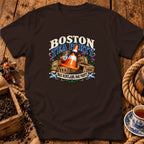 Dark brown t-shirt featuring a graphic with crates of tea, a traffic cone wearing sunglasses, and text reading Boston Tea Party Nae Scotland, Nae Party.