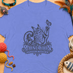 Maine Coon cat playing with butterfly graphic on lavender t-shirt.