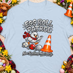 Cartoon chicken with scarf rolls Easter eggs past a cone, text "Egg Roll Patrol".