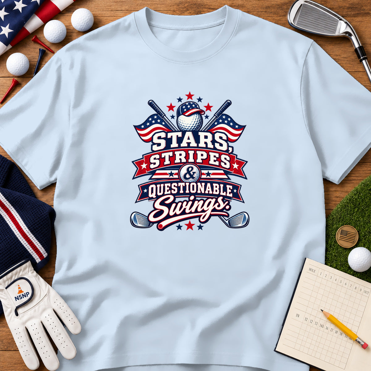 Light blue t-shirt displaying a patriotic golf graphic that reads "Stars, Stripes, & Questionable Swings" surrounded by golf accessories.