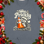 T-shirt graphic of a hedgehog holding an orange traffic cone with "Wee Prickly" and "Nae Scotland, Nae Party" text.