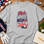 A grey t-shirt featuring a golf-themed patriotic graphic surrounded by golf balls, tees, a glove, and a scorecard on a wooden surface.