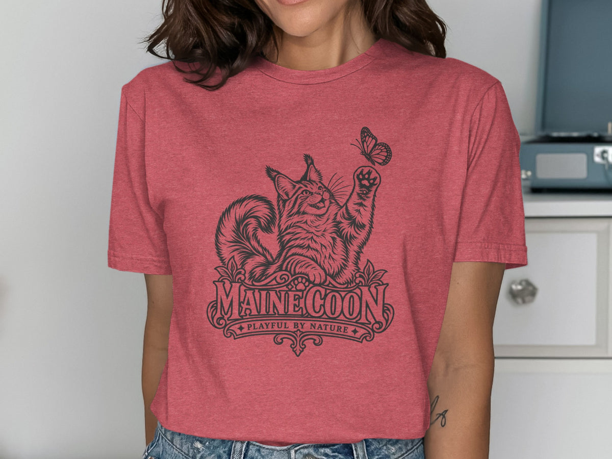 T-shirt with a black graphic of a Maine Coon cat playing with a butterfly, with text.