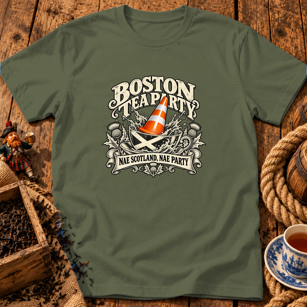 Olive green t-shirt featuring a humorous graphic with text reading "Boston Tea Party" and "Nae Scotland, Nae Party."
