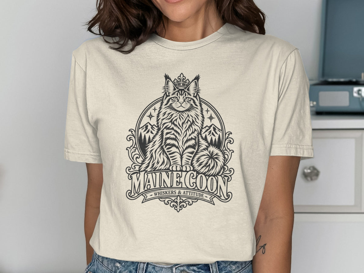 Maine Coon cat wearing a crown, with mountains and stars, text reads "MAINE COON WHISKERS & ATTITUDE".