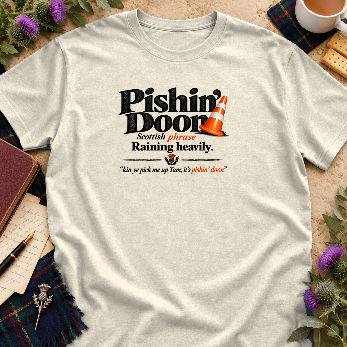 Off-white t-shirt featuring black and orange text that reads Pishin Doon with a traffic cone.